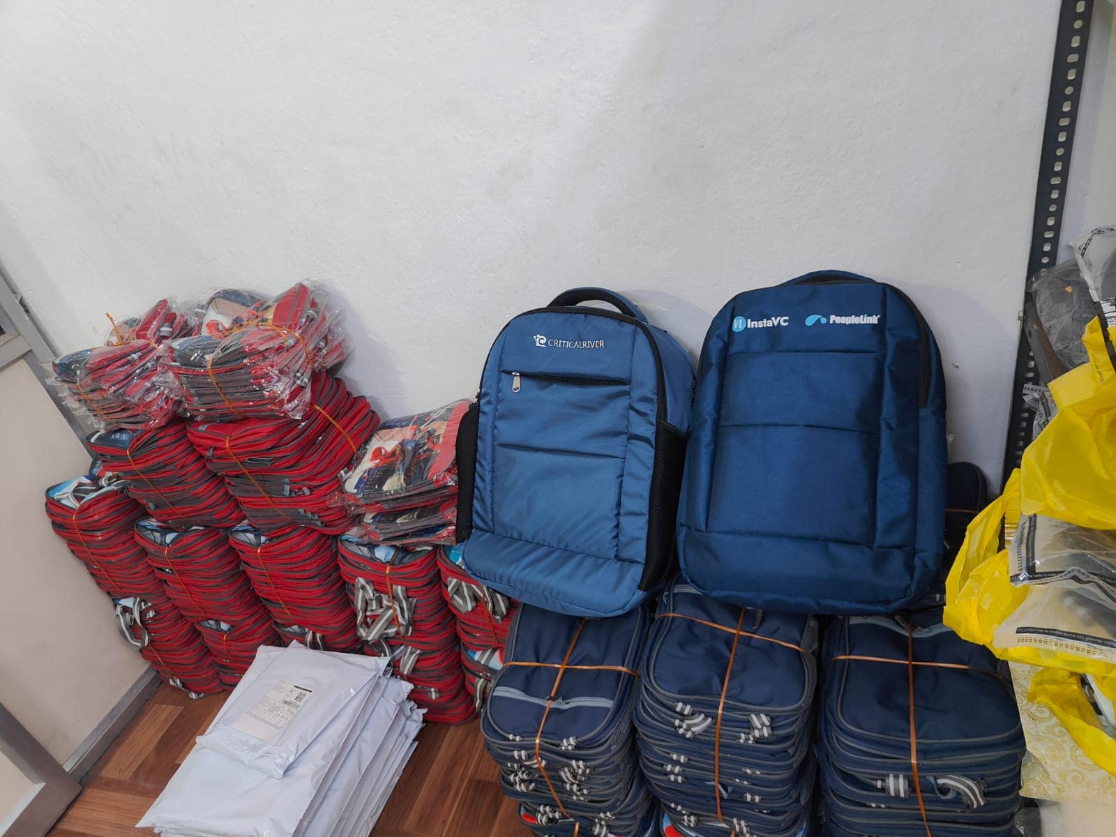 Corporate laptop backpacks branded for three companies, stacked ready for dispatch